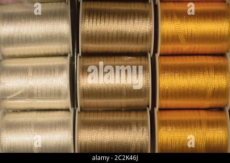 Cutout texture closeup on coils of colored sewing threads white,gold and yellow. Stock Photo