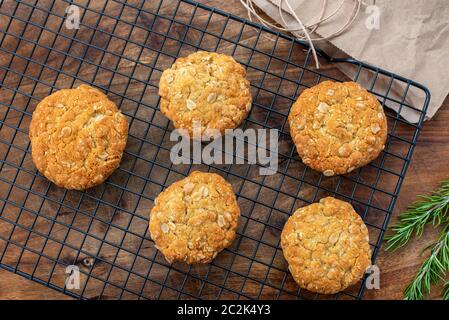 Anzac biscuits, a traditional Australian homemade oat cookie made with golden syrup enjoyed on Anzac Day pictured with rosemary, a symbol of remembrance Stock Photo