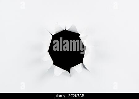 Breakthrough torn big black hole in white paper isolated background Stock Photo