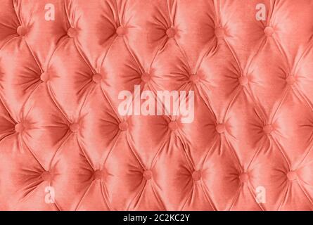 Coral toned pink velvet capitone textile background, retro Chesterfield style checkered soft tufted fabric furniture decoration with buttons, close up Stock Photo
