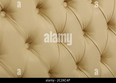 Close up background texture of beige white capitone genuine leather, retro Chesterfield style soft tufted furniture upholstery with deep diamond patte Stock Photo