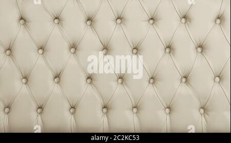 Close up background texture of beige white capitone genuine leather, retro Chesterfield style soft tufted furniture upholstery with deep diamond patte Stock Photo