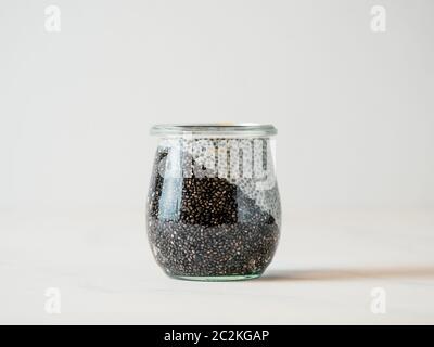 Healthy breakfast concept and idea - two colors chia pudding on white tabletop. Glass jar with black charcoal and white vegan milk chia pudding. Copy Stock Photo