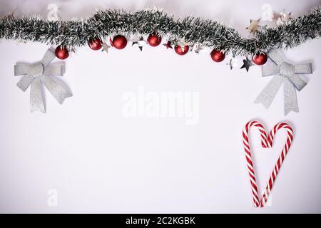 Christmas composition. Garland with red balls, stars, glittery bows and heart made of candy canes on white background. Christmas, winter, new year con Stock Photo