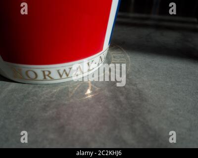 Red cup with Norwegian text reflected on the floor. Stock Photo