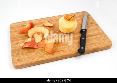 a peeled apple on a wooden board Stock Photo