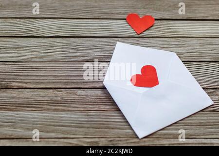 two red paper hearts on white open envelope against gray wooden background Stock Photo