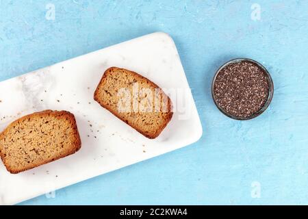 Chia seed cake slices, shot from the top on a marble cutting board and a blue background with a place for text, healthy vegan ba Stock Photo