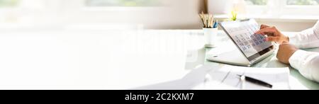 Close-up Of A Man Planning The Schedule On An Open Laptop Over The White Desk Stock Photo