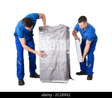 Two Male Movers Wrapping The Home Appliances With Plastic Wrap On White Background Stock Photo