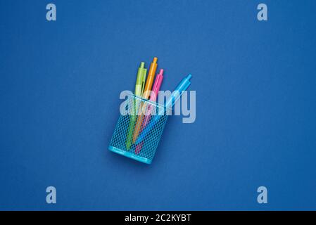 blue iron stand with multi-colored plastic ball pens on a blue background, top view Stock Photo