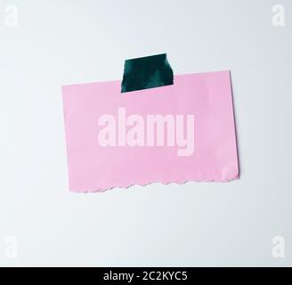 blank pink sheet of paper stuck with green sticky tape on a white background, place for text Stock Photo