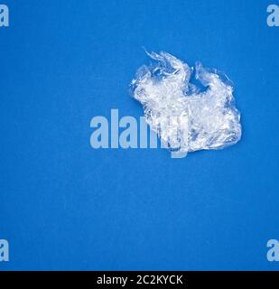 crumpled transparent stretching plastic film for packaging products on a blue background, close up Stock Photo