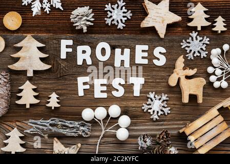 White Letters Building The Word Frohes Fest Means Merry Christmas. Wooden Christmas Decoration Like Tree, Sled And Star. Brown Wooden Background Stock Photo