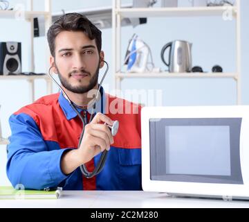 Young repairman fixing and repairing microwave oven Stock Photo