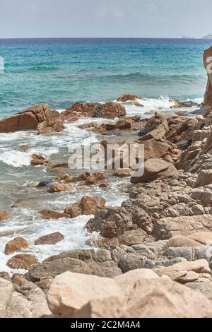 Vertical shot of a cliff that plunges into the rough and wavy sea. Stock Photo