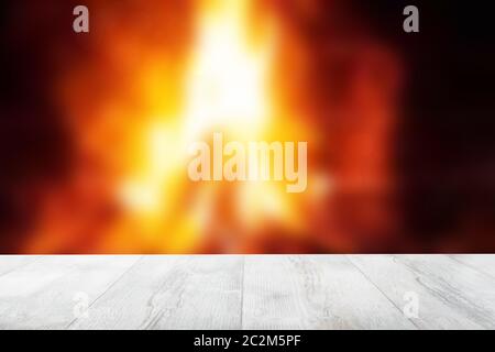 Empty wooden deck table over abstract blurred fireplace with blazing flames at night. Template for your product display montage. Beautiful Christmas b Stock Photo
