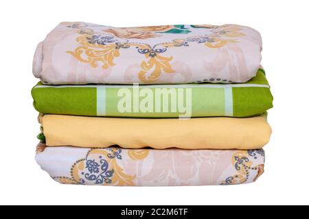 Bed linen isolated. Close-up of a stack or pile of colorful folded bed linen or duvet covers isolated on a white background. Macro of washed and irone Stock Photo