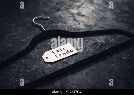 ethical fashion concept, velvet clothes hanger with Fair Trade label on it on black background Stock Photo