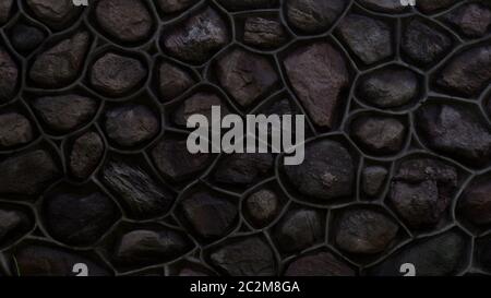 Dark wall made of stone and cement. Mosaic of rocks used as tiles. Shiny stone fence. Decorative texture from natural material. Background, pattern Stock Photo