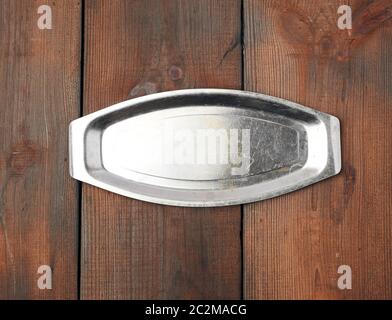 oval iron empty plate, brown wooden background, top view Stock Photo