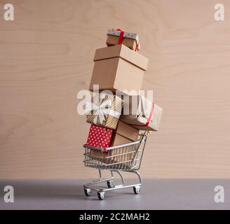high pyramid of gift boxes in toy shopping cart on wooden background Stock Photo