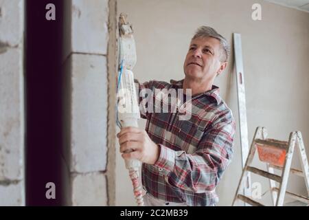 Plasterer smoothing interior wall of new homes with machine Stock Photo