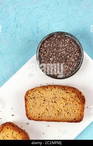 Chia seed cake, overhead shot on a marble cutting board and a blue background with copyspace, healthy vegan baking Stock Photo