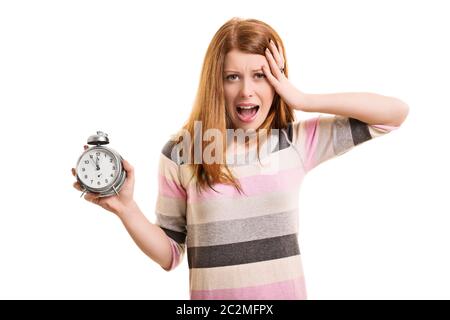 Being late concept. A portrait of a young woman holding an alarm clock, panicking about being late, isolated on white background. Stock Photo