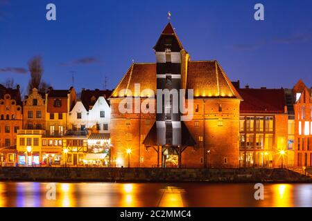 Old harbour crane and city gate Zuraw in old town of Gdansk, Dlugie Pobrzeze and Motlawa River at night, Poland Stock Photo