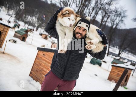 Brown man carrying a husky in his back Stock Photo