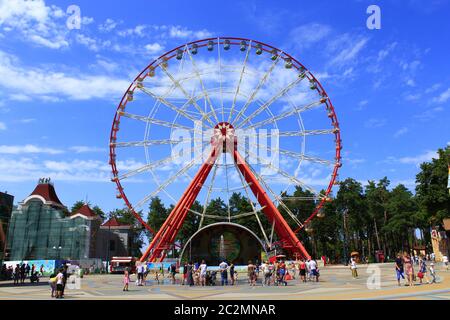 Fferris wheel and people walk in Gorky park in Kharkiv. People walking in city park with entertainme Stock Photo