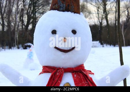 Snowman cheerful in the snow. New Year Attribute. Christmas symbol. Snowman with red scarf Stock Photo