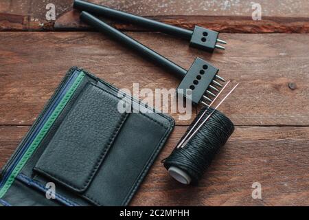 black leather wallet on wooden boards and leather tools Stock Photo