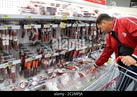 Man choosing goods in supermarket with large assortment of ketchup sauces and mayonnaise Stock Photo