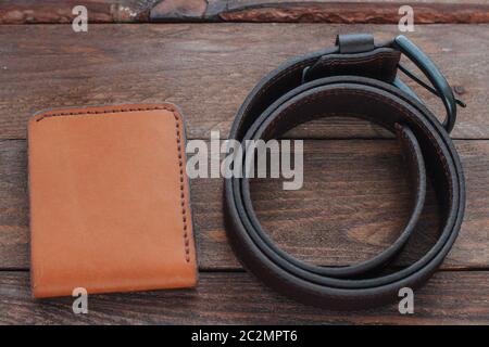 Brown leather wallet with dark brown mens belt on wooden desk. Stock Photo