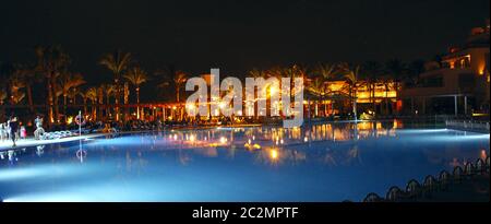 Swimming pool and evening hotel on holidays. People relax in evening near pool Stock Photo