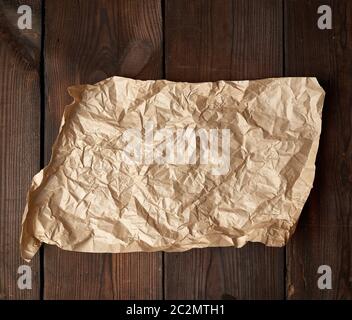 empty torn piece of brown crumpled baking paper on a table of boards, top view Stock Photo