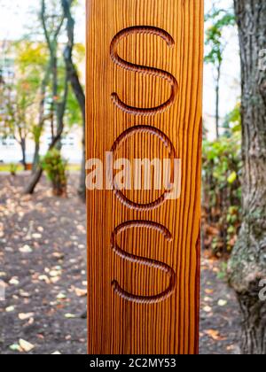 Sos is written on a wooden post. Help. Stock Photo