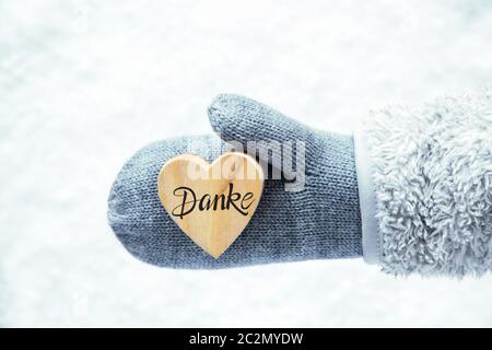 Heart With German Calligraphy Danke Means Thank You. Hand In A Glove With Fleece And Snow. Stock Photo