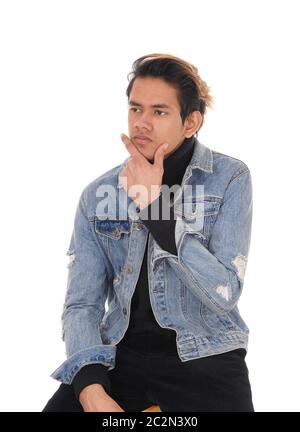 A young handsome man sitting in a jeans jacket and black pants on a chair, resting, isolated for white background Stock Photo