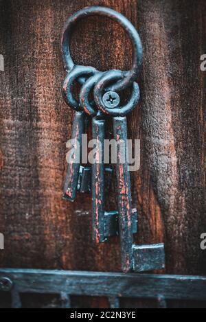 Some old rusty keys hanging on a wooden key chain Stock Photo