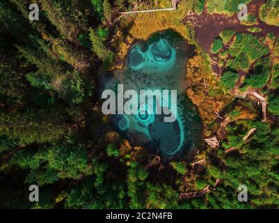 Beautiful Geyser (blue, silver) lake with thermal springs that periodically throw blue clay and silt from the ground. Aerial drone view. Aktash, Altai Stock Photo