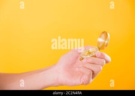 Hand holding antique brass compass isolated on yellow background with copy space for text Stock Photo