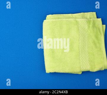 folded bath terry light green towel on a blue background, top view Stock Photo