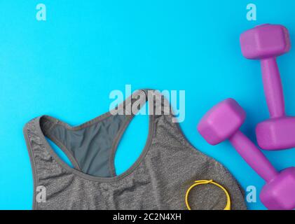 pair of purple plastic dumbbells, gray sports shirt on a blue background, set for sports, flat lay Stock Photo