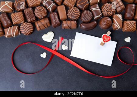 Chocolate pralines with white card for Valentines day on black background Stock Photo