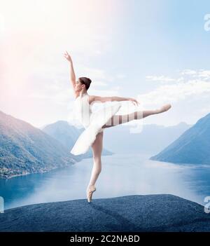 Grace ballerina keep the rack in studio, lake and mountains on background Stock Photo