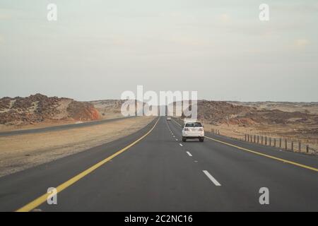 Highway Desert / Saudi Arabia - January 20, 2020: beautiful straight highway with vehicles surrounded by rock mountains in Saudi Arabia Stock Photo