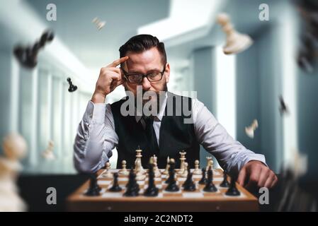 Pensive male chess player in glasses calculate movies and game strategy against chessboard. Figures flying around chessplayer. Intelligence competitio Stock Photo